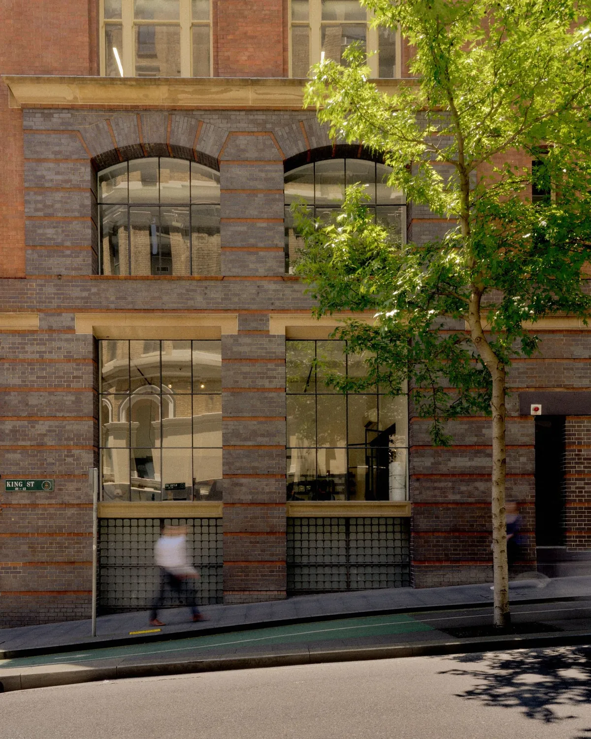 The heritage sandstone and brick frontage of Skittle Lane’s CBD flagship, with arched windows and a plane tree outside