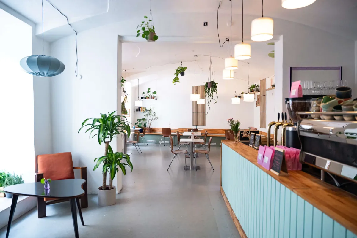 The room at bistro deppat in Vienna, with a mint-green counter, an espresso machine, hanging plants and tables at the back
