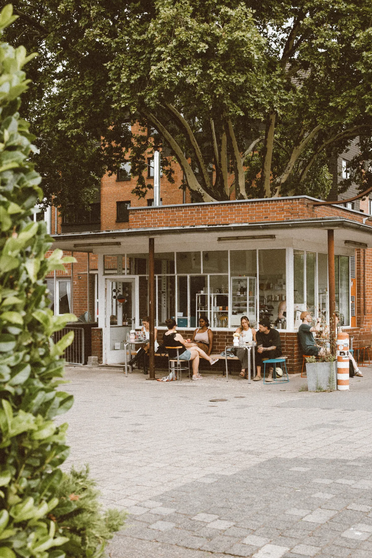 The former gatehouse that houses Radix & Anima on the Lindgens Areal in Cologne-Mülheim, with guests at tables under its canopy